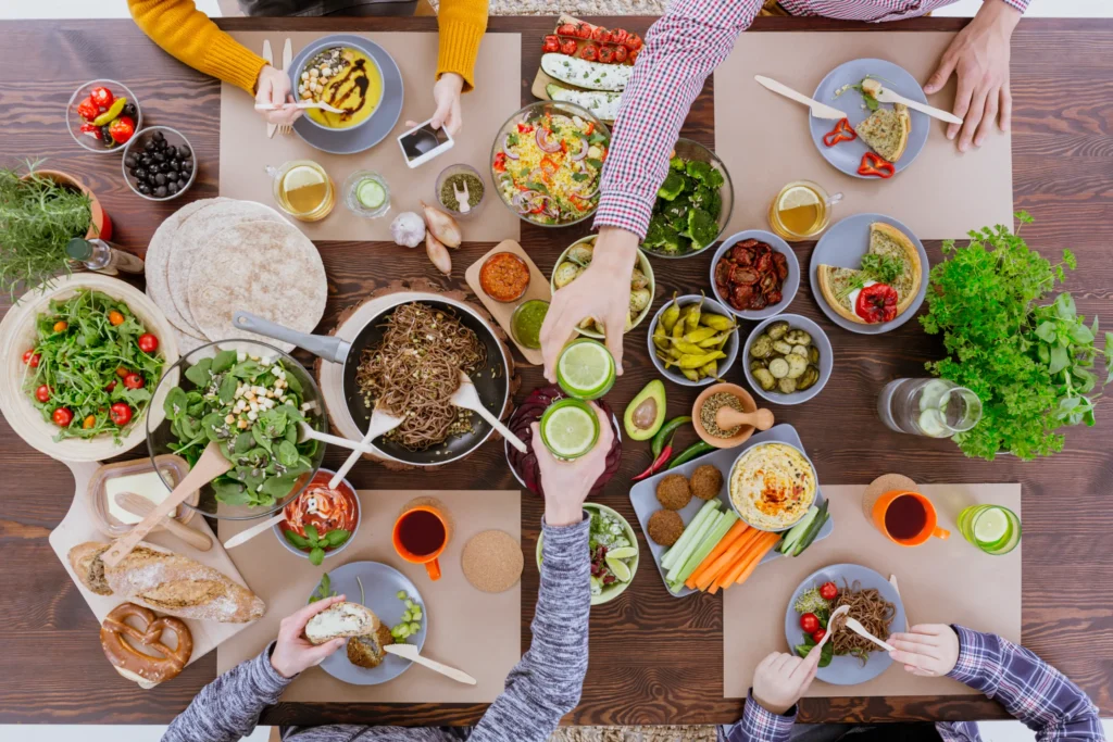 l'immagine rappresenta una tavola di amici ricca di piatti vegetariani